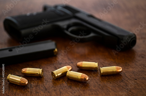 Gold bullets and pistol on wooden surface photo