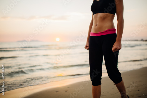 Runner woman jogging on beach in a sports bra top.Fit fitness woman training and working out outside as part of a healthy lifestyle.Fitness woman running at sunset.Determination and resolution concept