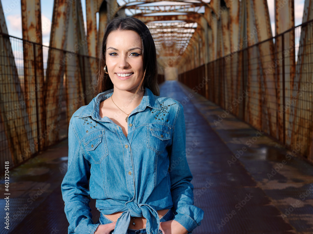 Φωτογραφία young pretty woman wearing cowboy clothes and walking along the walkway of a bri