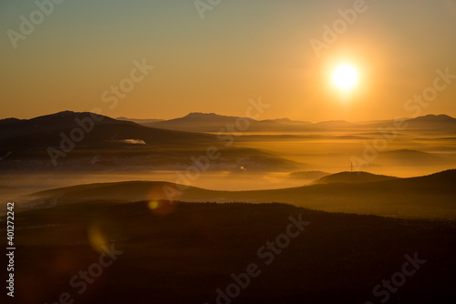 the sun sets below the horizon and illuminates the fog in the valley with a yellow light © Павел Чигирь
