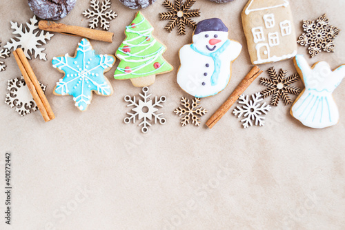 Fototapeta Naklejka Na Ścianę i Meble -  Gingerbread painted colored gingerbread cookies and spices and snowflakes on a craft background close-up. Christmas celebration concept. New Year's food. Copy space