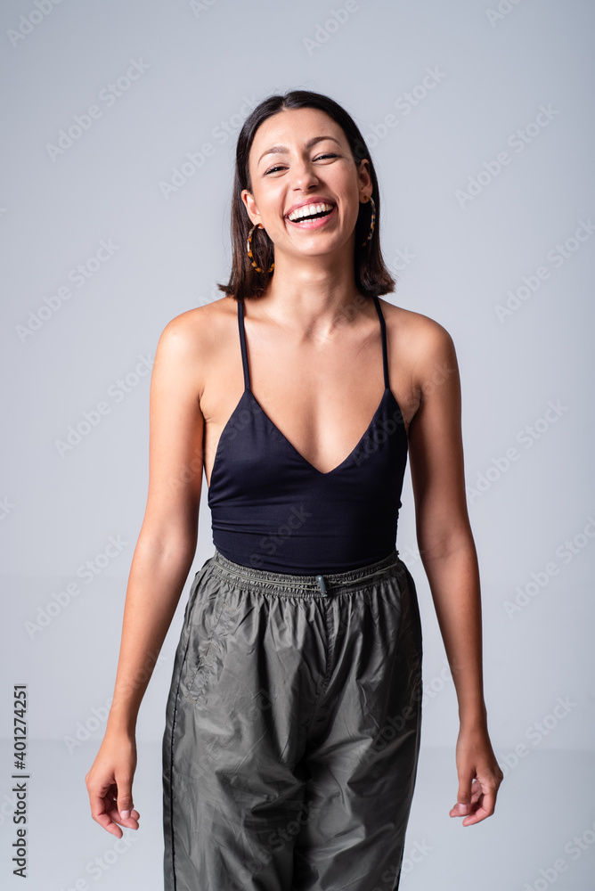 Beautiful smiling female wearing black low neckline top standing against white background in studio and looking at camera happily Beautiful smiling female wearing black low neckline top standing against white background in studio and looking at camera happily