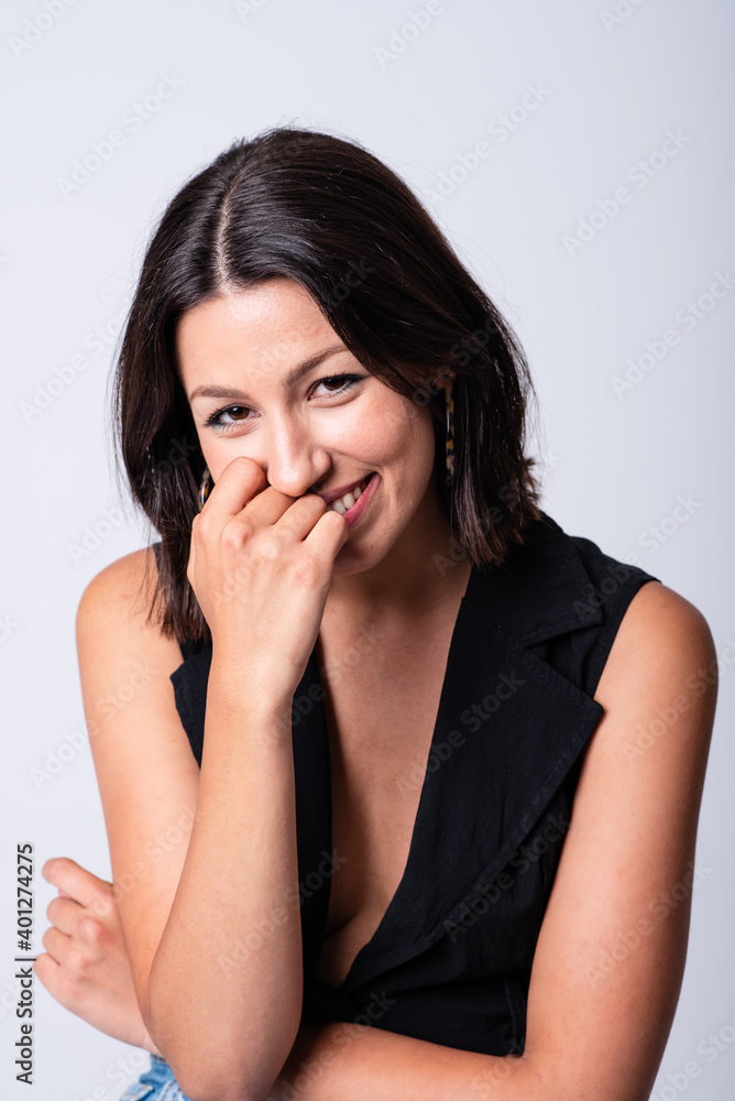 Beautiful smiling female wearing black low neckline top standing against white background in studio and looking at camera happily Beautiful smiling female wearing black low neckline top standing against white background in studio and looking at camera happily