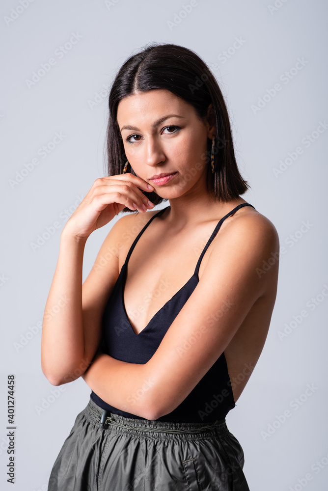 Beautiful female wearing black low neckline top standing against white background in studio and looking at camera Beautiful female wearing black low neckline top standing against white background in studio and looking at camera