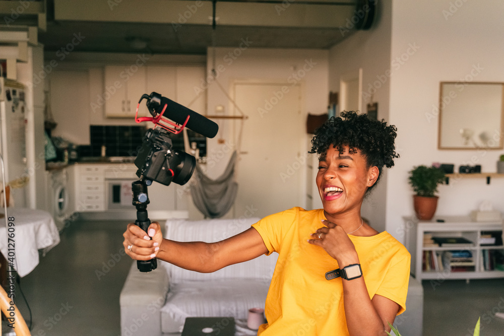 Cheerful young African American female blogger recording video while preparing content for social networks at home Cheerful young African American female blogger recording video while preparing content for social networks at home