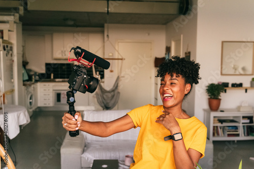 Cheerful young African American female blogger recording video while preparing content for social networks at home photo