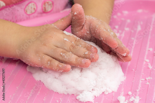 Child plays with artificial snow for home decoration