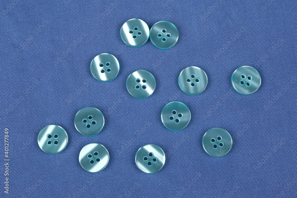 Plastic shiny buttons for clothes on a fabric background. Fashion and clothing. Factory industry Plastic shiny buttons for clothes on a fabric background. Fashion and clothing. Factory industry