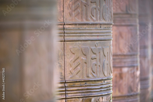 Old stone Tibetan rolls with sacred mantra consisting of sanskrit inscription near temple photo