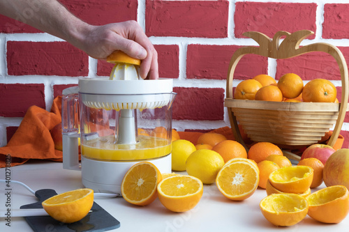 a man squeezes an orange on a juicer, squeezed and whole oranges on the table