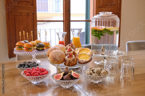 Buffet set with sweet pastry and mini burgers arranged near fresh fruits and berries on table with natural drinks in hotel restaurant photo