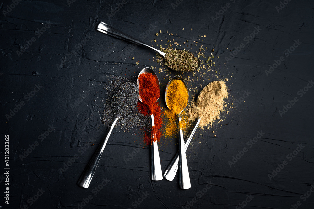 Spices in metal spoon on black background Spices in metal spoon on black background