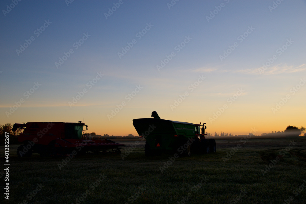 Silhouette of combine harvester on the field in the morning