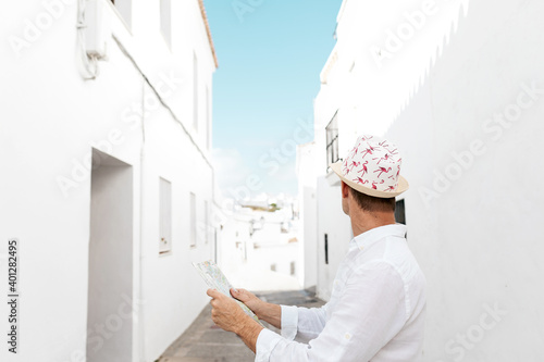 Side view of glad male traveler orienting himself with map on aged street in Greece photo