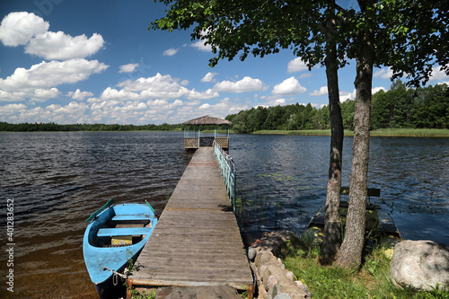 Summer landscape in sunny weather with wooden pier and boat on the lake photo