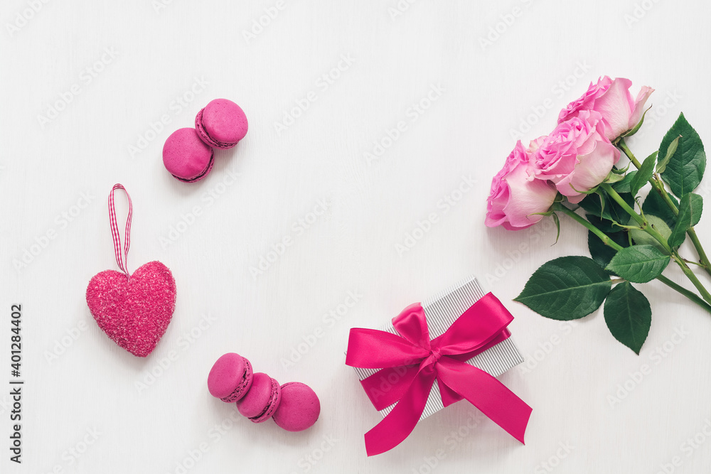 Valentine's Day. Beautiful composition - roses, gift box, purple macaroons and heart. White painted wood background. Greeting card. Top view, flat lay.