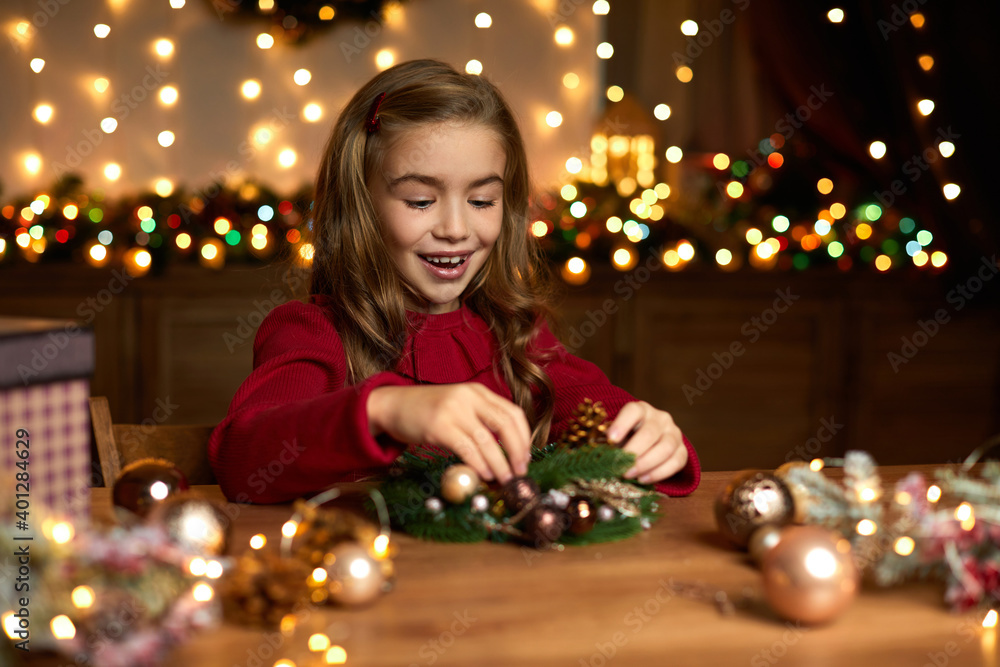 happy cute little child girl makes a handmade Christmas wreath at home. happy cute little child girl makes a handmade Christmas wreath at home.