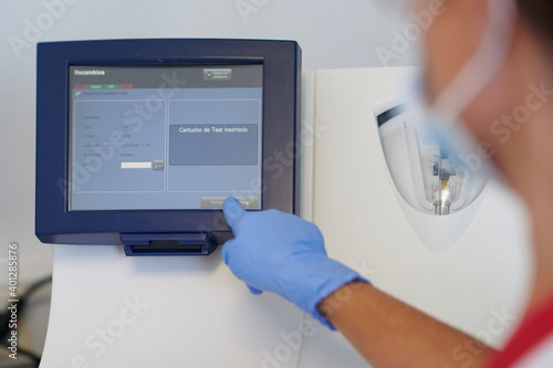Crop unrecognizable medic choosing option on monitor of medical diagnostic equipment while working in laboratory