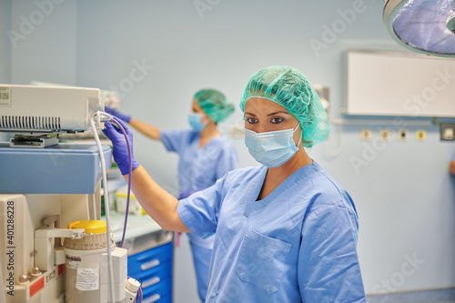 Side view of female medic in uniform touching monitor of medical equipment in clinic