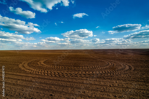 plowed field prepared for sowing and tracks of tractor tires, beautiful blue ...