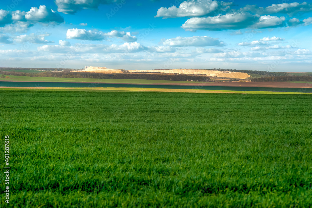 Obraz premium green field of winter and agricultural lands and quarries in the distance