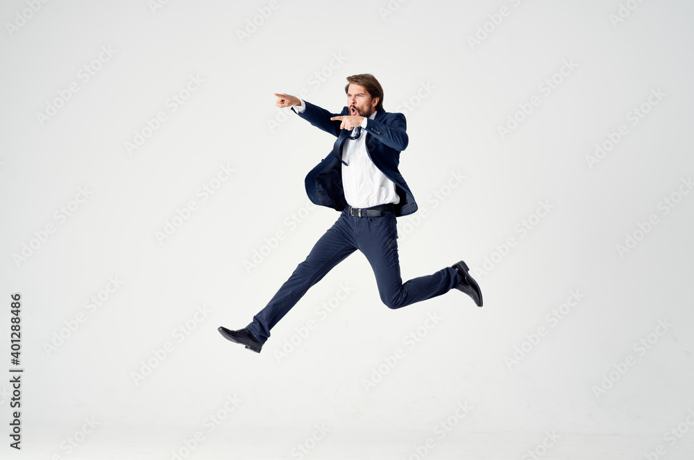 Energetic business man in a blue suit jumps up on a light background success joy emotions