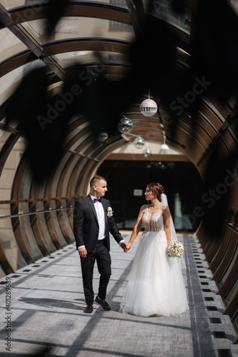 Happy just married couple walking beautiful round window in wedding day