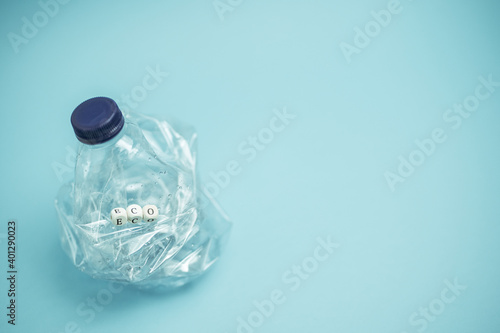 Crumpled plastic bottle placed on blue background in studio demonstrating concept of waste recycling photo