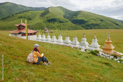 Side view full length of Asian female backpacker enjoying vacation near oriental shrine located in green valley in China