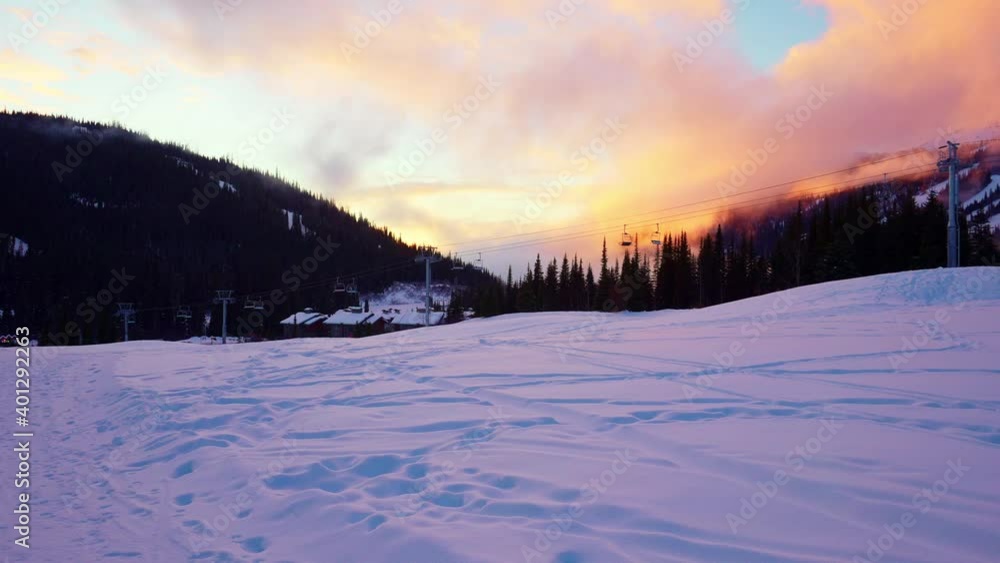 Empty moving cableway lift chairs on the snowy ground and trees at sunset Empty moving cableway lift chairs on the snowy ground and trees at sunset