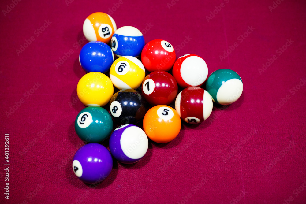 Group of snooker multicolored balls lays as pyramid on the table. Closeup view. Billiard red table with cue and balls. Leisure, hobby and entertainment concept Group of snooker multicolored balls lays as pyramid on the table. Closeup view. Billiard red table with cue and balls. Leisure, hobby and entertainment concept