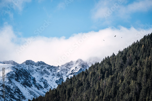 Majestic panoramic scenery of rough rocky slopes of Pyrenees mountain range covered with snow under cloudy sky in El Pas de la Casa photo