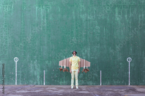 Male in handmade cardboard wings standing looking up while dreaming about achieving success
