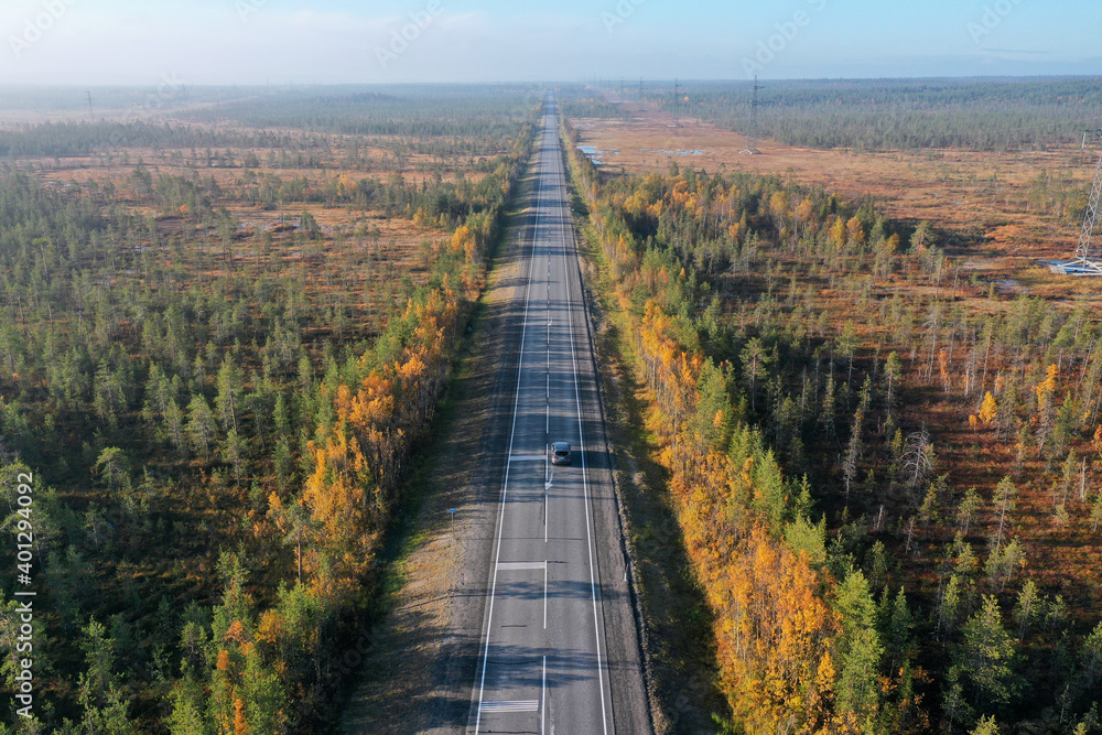 Drone view of picturesque curved roadway leading through valley with colorful trees in autumn Drone view of picturesque curved roadway leading through valley with colorful trees in autumn