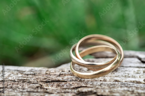 Close-up of a ring with three rings on wooden background. Wedding jewelry in gold, white gold and rose gold. macro shot with selective focus