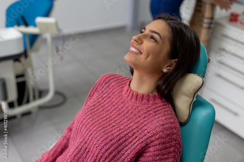 Portrait of a young woman with a beautiful smile sitting on the dentist's chair and waiting for her teeth treatment. 