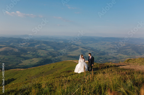 Wedding couple in mountains. Bride and groom standing on the hill