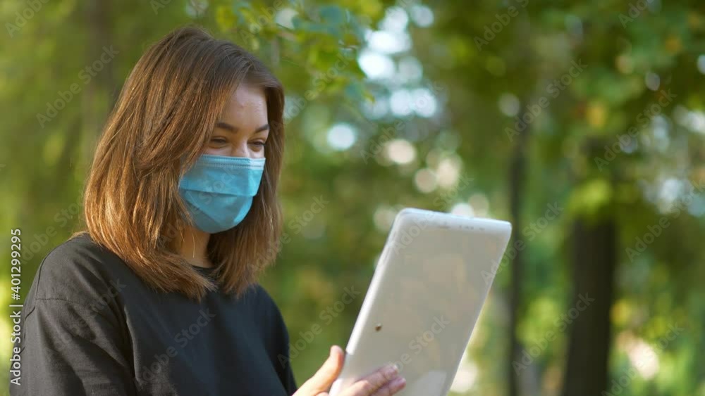 Woman in medical protective mask speaks via tablet computer Woman in medical protective mask speaks via tablet computer