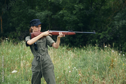 Woman With a weapon in hand, a hunting green jumpsuit is aiming fresh air 