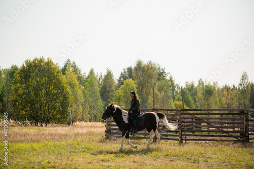 A pretty girl came to the country equestrian club and rides a horse through the fields in the fall.