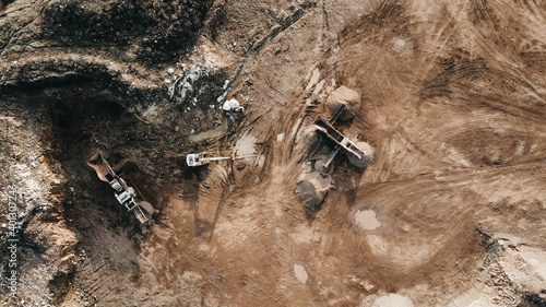 Aerial top down of Vast Excavation Site With Multiple Heavy Industry Vehicles during sunset after work.