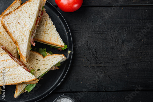 Fresh sandwiches with ingredients, on black wooden table, top view with copy space for text