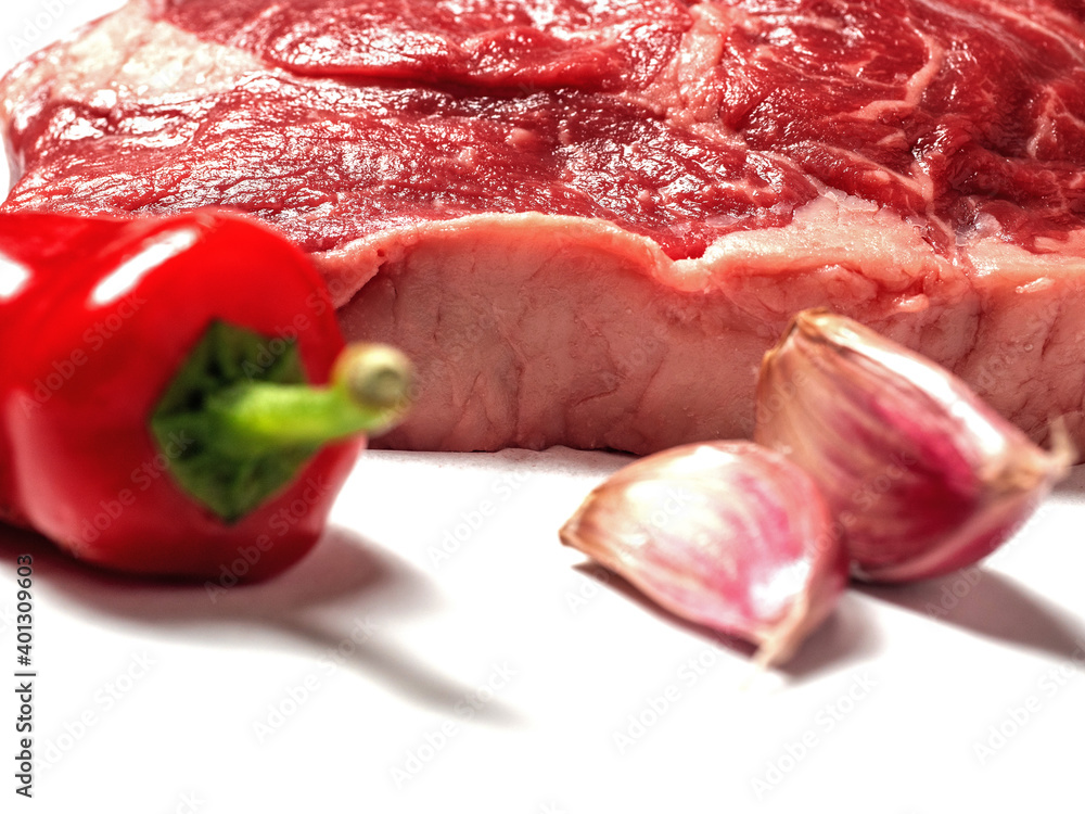 Fresh rib eye steak on a white background with rosemary herb, red chilly and garlic clove. Selective focus. Meat industry product, Premium high quality cut with rich marbling