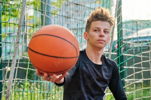 Close-up basketball ball in the hand of teenage guy