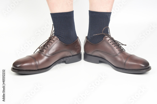 Male legs in socks and brown classic shoes on a white background