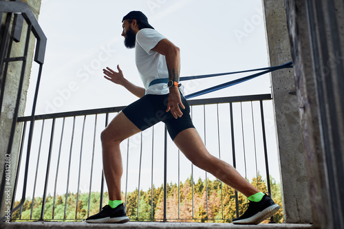 Concentrated male athlete running up stairs to make training more intensive. Sporty handsome young man training alone outdoors. Staircase workout concept
