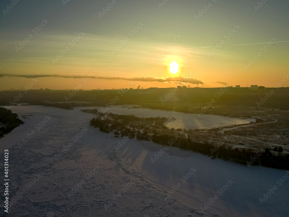 the sun rises over the city located on the banks of the river on a frosty winter morning