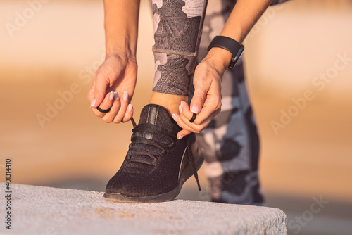 Close up of sporty fitness woman tying shoelaces. Preparing for workout