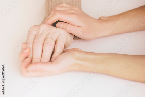 Young woman's hands hold grandmother's hands, an elderly patient. Handshake, caring, trust and support. Medicine, family and healthcare. © Zhanna