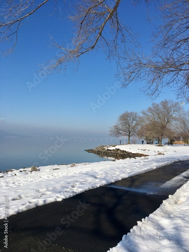 Winter scene, park, river, snow, blue sky, bare trees